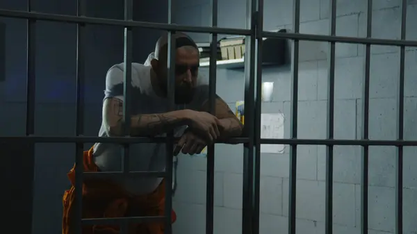 Depressed Male Prisoner Orange Uniform Stands Prison Cell Leaning Holding — Stock Photo, Image
