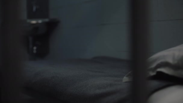犯人把橙色监狱制服 浴巾和卫生纸放在床上 有罪的罪犯或囚犯在狱中服刑 拘留中心或教养所 透过金属棒观看 — 图库视频影像