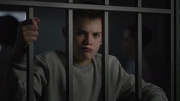Vit Tonåring Med Ansiktstatueringar Sitter Fängelse Håller Metallstänger Och Tittar — Stockvideo
