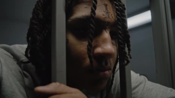 沮丧的有面部纹身的非洲裔美国少年罪犯被关进了监狱 关押着铁棍 年轻囚犯因在狱中犯罪而服刑 少年拘留中心 靠近点 — 图库视频影像