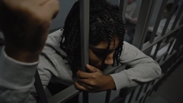 Расстроенный Афроамериканский Подросток Стоит Тюремной Камере Тюрьме Держит Металлические Решетки — стоковое видео