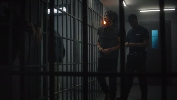 典狱长把新囚犯带进监牢 摘下手铐 非洲裔美国少年在狱中服刑 关押在监狱里的年轻囚犯 司法系统 透过金属棒观看 — 图库视频影像