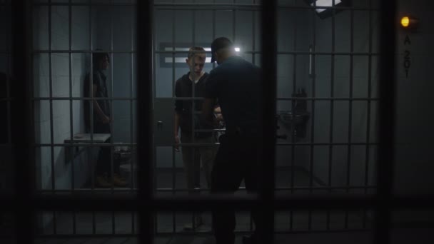 监狱长从站在铁栅栏后面的年轻囚犯身上摘下手铐 多族裔青少年在惩教设施或拘留中心服刑 狱中的有罪囚犯 — 图库视频影像