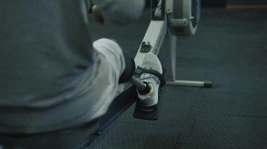 Modern spor salonunda ya da fitness merkezinde kürek çekme makinesi üzerinde protez bacak egzersizi yapan atletik bir adam. Fiziksel engelli motive bir sporcu profesyonel spor ekipmanları kullanarak güçlü bir antrenman yapıyor..