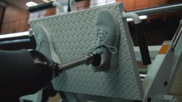 在现代体育馆或健身中心 在腿压机上进行义肢运动的运动员近身 有身体残疾的健康男子使用专业的体育器材进行力量训练 — 图库视频影像