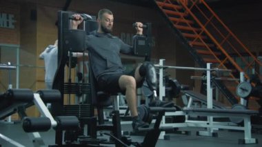 Modern fitness merkezinde protez bacak egzersizleri yapan yetişkin bir atletik. Fiziksel engelli motive bir sporcu profesyonel spor ekipmanları kullanarak güçlü bir antrenman yapıyor..