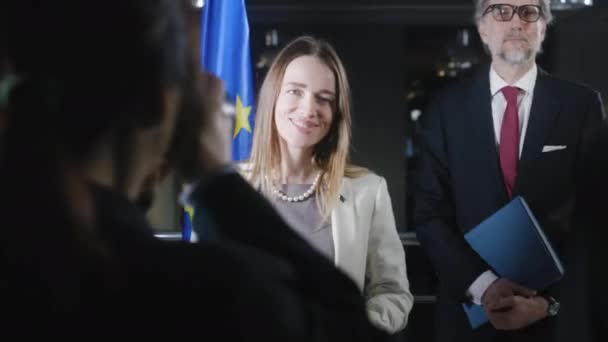 欧州連合のポジティブな女性代表は カメラをポーズし ジャーナリストに挨拶します 担当者は写真を撮ってテレビで放送する 記者会見の初めにEuの政治家 — ストック動画