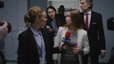 Kendine güvenen kadın politikacı basın sorularını yanıtlıyor ve hükümet binasının koridorunda yürüyen medyaya röportaj veriyor. Etrafı gazetecilerle çevrili meşgul bir diplomat. Basın kampanyası.