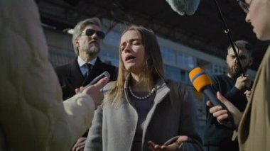 İki organizasyon temsilcisi basın sorularını yanıtlıyor ve dışarıda bir futbol stadyumunda röportaj veriyor. TV haberleri için basın toplantısında başarılı bir SEO röportajı. Gazeteciler basın kampanyasında kalabalıklar.