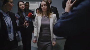 Meşgul bayan Amerikalı bakan TV basınına sıcak düğme sorunlarından bahsediyor, hükümet binasının koridorunda yürüyen medyaya röportaj veriyor. Etrafı gazetecilerle çevrili bir siyasetçi.