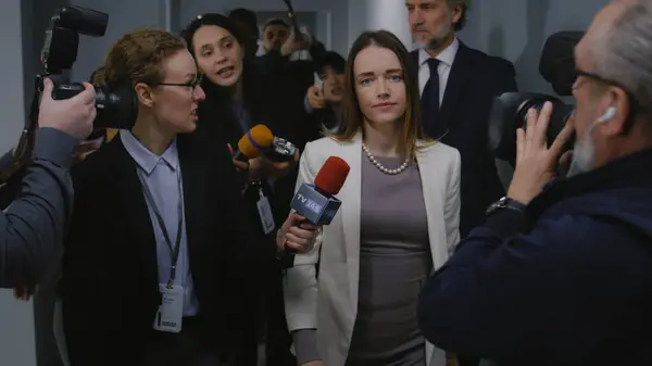 忙得不可开交的美国女部长在接受电视新闻采访时谈到了热点问题 并接受了在政府大楼走廊内行走的媒体采访 被大批新闻工作者包围的政治家 — 图库照片