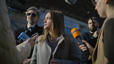 İki organizasyon temsilcisi basın sorularını yanıtlıyor ve dışarıda bir futbol stadyumunda röportaj veriyor. TV haberleri için basın toplantısında başarılı bir SEO röportajı. Gazeteciler basın kampanyasında kalabalıklar.