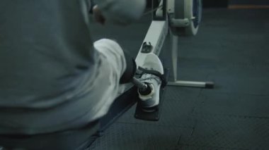 Modern spor salonunda ya da fitness merkezinde kürek çekme makinesi üzerinde protez bacak egzersizi yapan atletik bir adam. Fiziksel engelli motive bir sporcu profesyonel spor ekipmanları kullanarak güçlü bir antrenman yapıyor..