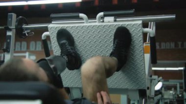 Modern fitness merkezinde bacak pres makinesinde protez bacaklı motive bir sporcu. Yapay bacaklı yetişkin bir sporcu profesyonel spor aletleri kullanarak güç eğitimi alıyor..