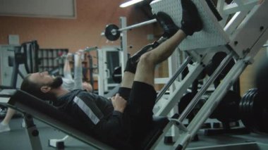 Modern fitness merkezinde protez bacak egzersizleri yapan atletik bir adam. Fiziksel engelli motive bir sporcu profesyonel spor ekipmanları kullanarak güçlü bir antrenman yapıyor..