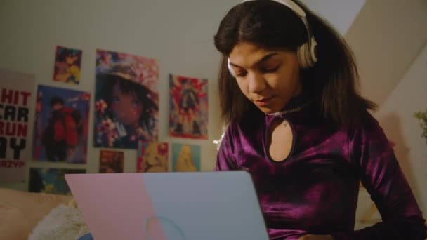 戴耳机的漂亮少年坐在房间的床上 用笔记本电脑上网 非裔美国女孩与朋友聊天或观看视频内容 在舒适的家中度过闲暇时间 — 图库视频影像