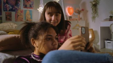 Afro-Amerikalı kız yerde oturuyor, internette telefonla sörf yapıyor. Asyalı gençler yatağa uzanır ve arkadaşlarıyla içeriği seyrederler. Çok ırklı kızlar birlikte boş vakitlerini evde geçirirler. Arkadaş ilişkisi.