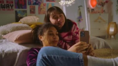 Afro-Amerikalı kız yerde oturuyor ve telefonla internette sörf yapıyor. Asyalı ergen yatakta yatar ve telefonda izler. İki farklı etnik gruptan kız telefonla fotoğraf çekiyor. Arkadaş ilişkisi.