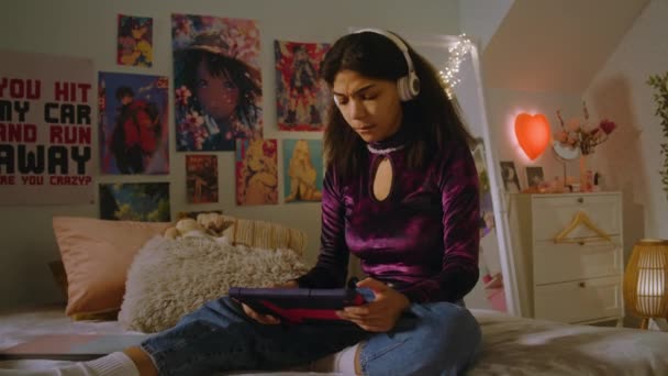 Красивый Подросток Наушниках Сидит Кровати Своей Комнате Занимается Серфингом Интернете — стоковое видео