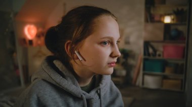 Genç güzel bir kız akıllı telefon kullanır, kulaklıkla ses çıkarır, sonra da yatak odasında rahat bir şekilde oturan arkadaşıyla konuşur. Beyaz tenli genç boş zamanlarını gündüzleri evde geçirir. Yaşam tarzı kavramı.