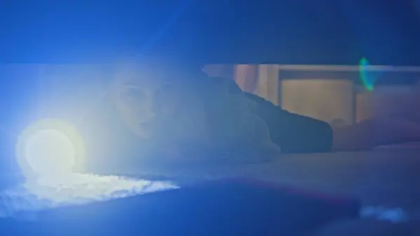 カカシアのティーンエイジャーは現代のライトルームに来ます 懐中電灯のある若い美しい女の子は 寝室の大きなベッドの下にデジタルタブレットのコンピュータを見つけようとします ベッドの下から撮影 ライフスタイルコンセプト — ストック写真