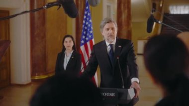 Gazeteciler, Amerika Başkanı 'nın basın toplantısında ilham verici siyasi konuşmasını bitirdiğini alkışlıyorlar. Politikacı Beyaz Saray 'da basın için röportaj veriyor. Arka planda Amerikan bayrakları.