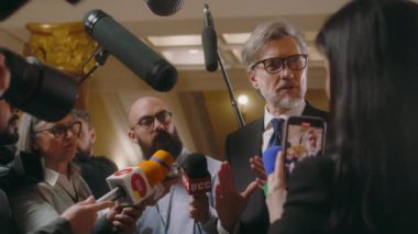 Politikacı basın sorularını yanıtlıyor ve televizyon haberleri için röportaj veriyor. Etrafı gazetecilerle çevrili olgun bir diplomat. Basın toplantısı. İlham verici bir konuşma. Yavaş çekim.