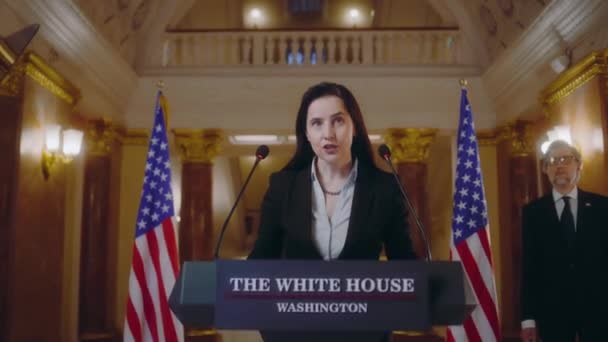 女性報道官がトリビューンに来て ホワイトハウスで政治演説を行った 米国の女性政治家は メディアやテレビの記者会見で発言している 背景にあるアメリカの国旗 — ストック動画