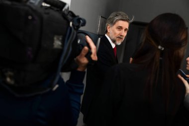 Olgun organizasyon temsilcisi basın sorularını yanıtlıyor ve parlamento koridorunda yürüyen TV haberleri için röportaj veriyor. Parti temsilcisi, etrafı televizyon gazetecileriyle çevrili. Basın kampanyası.