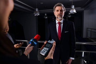 Güvenilir ve ciddi erkek diplomat veya iş adamı gazetecilerle konuşuyor ve hükümet binasında medya ve televizyon için röportaj veriyor. Basın toplantısında siyasetçinin siyasi konuşması.