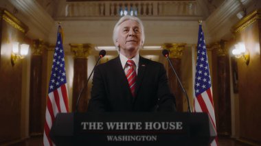 Amerika Birleşik Devletleri 'nin olumlu başkanı Beyaz Saray' da ilham verici bir konuşma yaptı ve sonra ayrıldı. Üst düzey ABD bakanı basın ve televizyon kampanyasında konuştu. Arka planda Amerikan bayrakları.