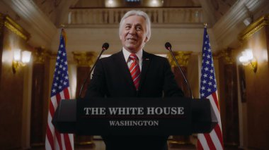 Amerika Birleşik Devletleri 'nin olumlu başkanı Beyaz Saray' da ilham verici bir konuşma yaptı ve sonra ayrıldı. Üst düzey ABD bakanı basın ve televizyon kampanyasında konuştu. Arka planda Amerikan bayrakları.
