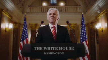 Amerika Birleşik Devletleri 'nin olumlu başkanı Beyaz Saray' da ilham verici bir konuşma yaptı ve sonra ayrıldı. Üst düzey ABD bakanı basın ve televizyon kampanyasında konuştu. Arka planda Amerikan bayrakları.