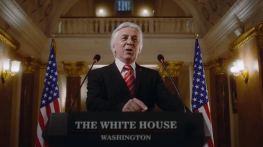 Amerika Birleşik Devletleri 'nin ciddi başkanı Beyaz Saray' da ilham verici bir siyasi konuşma yapıyor. Üst düzey ABD hükümet temsilcisi basın toplantısında basın açıklaması yaptı. Arka planda Amerikan bayrakları.