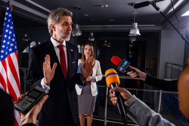 Ciddi Amerikalı erkek politikacı gazetecilerle konuşuyor, soruları cevaplıyor ve hükümet binasında medya ve televizyon haberleri için röportaj veriyor. Basın toplantısı sırasında Birleşik Devletler Kongre Üyesi.