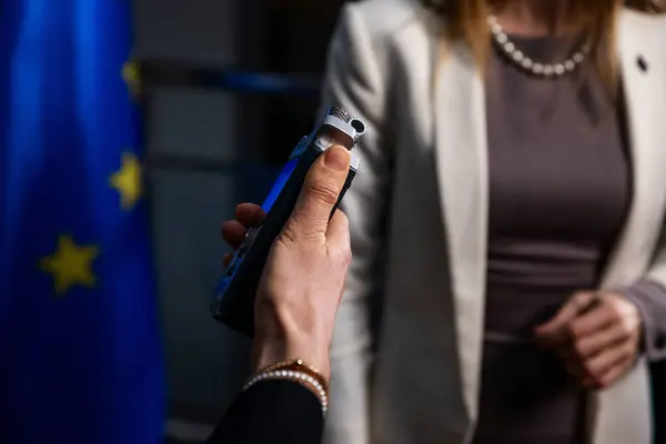 记者手中拿着录音机的特写镜头 其目标是拿着欧盟国旗的女政治家 — 图库照片