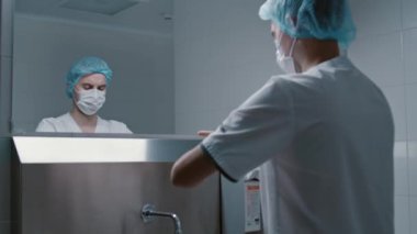 Cerrah doktor ameliyattan önce ellerini yıkıyor. Özel modern bir odada. Klinikte paslanmaz bir lavabo ile ameliyata hazırlanıyor.