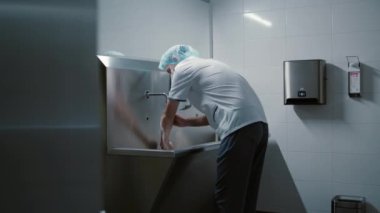 Cerrah doktor ameliyattan önce ellerini yıkıyor. Özel modern bir odada. Klinikte paslanmaz bir lavabo ile ameliyata hazırlanıyor.