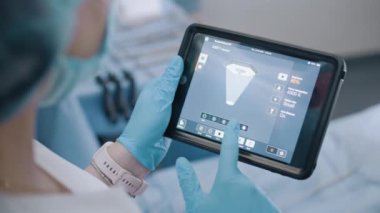 Bir cerrahi asistan, dijital tablet kullanarak cerrahi operasyona başlamadan önce ameliyathanedeki aydınlatma armatürünün ışığını ayarlar..