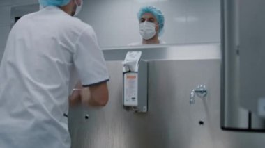 Cerrah doktor ameliyattan önce ellerini yıkıyor. Özel modern bir odada. Klinikte paslanmaz bir lavabo ile ameliyata hazırlanıyor.