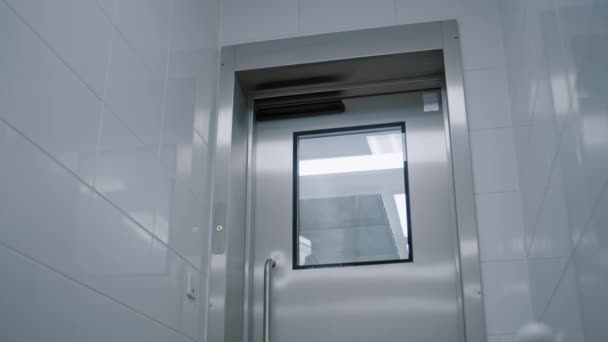 外科医生沿着走廊走着 通过装有自动无接触式门窗的现代铁门进入手术室 — 图库视频影像