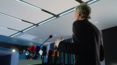 Olgun bir politikacı ya da eylemci konferans odasında Tribün 'den konuşma yaptı. Erkek basın görevlisi soruları cevaplıyor, televizyon veya medya için röportaj veriyor. Yavaş çekim.