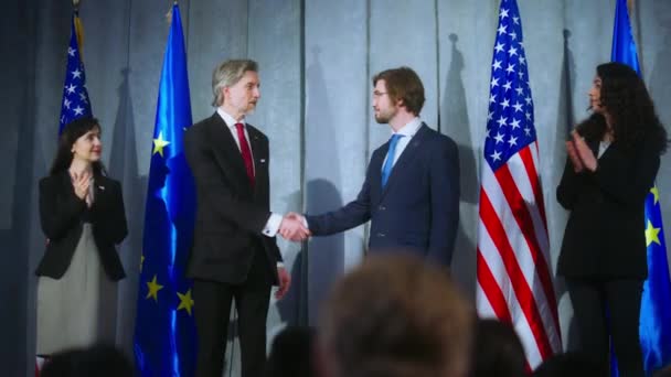 欧州連合 の代表で成熟した米国大統領は記者会見の後に握手した ジャーナリストとの会談中に世界の指導者 アメリカとEuの旗を背景に — ストック動画