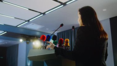 Kadın organizasyon temsilcisi konferans odasında basın kampanyası sırasında Tribün 'ün konuşmasını duyurdu. Politikacı soruları cevaplıyor, televizyon veya medya için röportaj veriyor. Yavaş çekim.