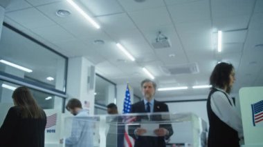 Olgun ABD 'li işadamı veya politikacı oy pusulasını sandığa koydu. Basın, oy verdikten sonra adamın fotoğrafını çekiyor. Çeşitli Amerikan halkı oy kullanma merkezindeki kabinlerde oy kullanıyor. Amerika Birleşik Devletleri Seçim Günü.