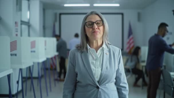 成熟した女性の肖像画 アメリカ合衆国選挙の有権者 ビジネスウーマンはカメラで話し 現代の投票所で投票するよう求めている 投票ブースの背景 市民の義務に関する概念 — ストック動画