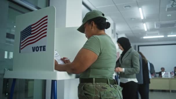 アメリカ陸軍の女性兵士が投票所でブースに投票 アメリカ合衆国の国民選挙の日 アメリカ合衆国大統領候補の政治的競争 市民の義務に関する概念 ドリー ショット — ストック動画