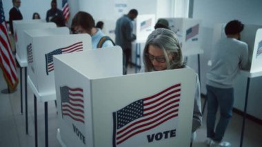 Oy merkezindeki kabinde yaşlı bir kadın oy veriyor. Birleşik Devletler 'de Ulusal Seçim Günü. ABD başkan adaylarının siyasi ırkları. Vatandaşlık görevi ve vatanseverlik. Ağır çekim. Dolly vurdu..