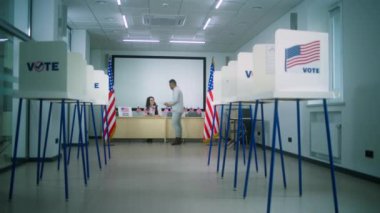 Afrika kökenli Amerikalı erkek oy kullanma merkezindeki kadın oy pusulasından oy pusulasını alır ve oy verme kabinine yürür. Amerika Birleşik Devletleri 'nde Ulusal Seçim Günü. Vatandaşlık görevi ve demokrasi.