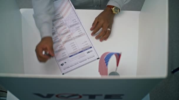 关闭了非裔美国人填写纸公告在投票亭与美国国旗 匿名的美国公民在投票站投票给总统 美利坚合众国的选举日 — 图库视频影像